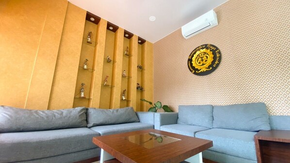 Una sala moderna con un sofá gris, una mesa de centro de madera y una pared decorativa con estantes que exhiben figuritas.