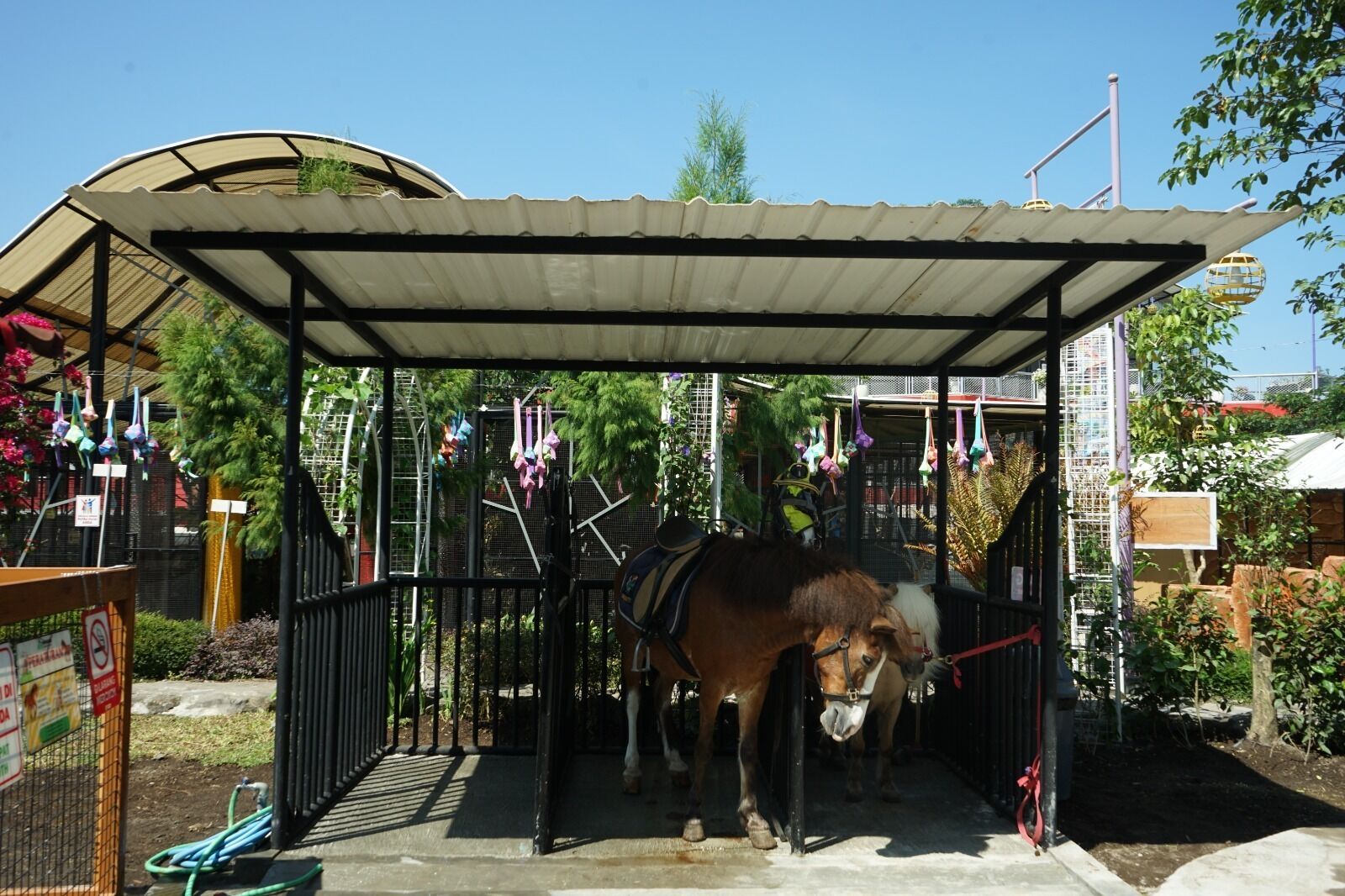 Un establo para caballos con techo de metal y zona cercada.