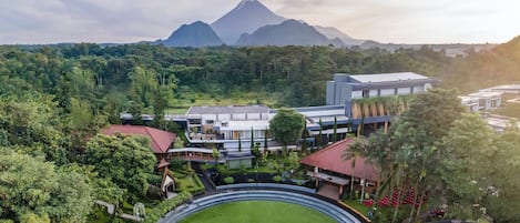 A resort with modern architecture, lush greenery, and a mountain backdrop.