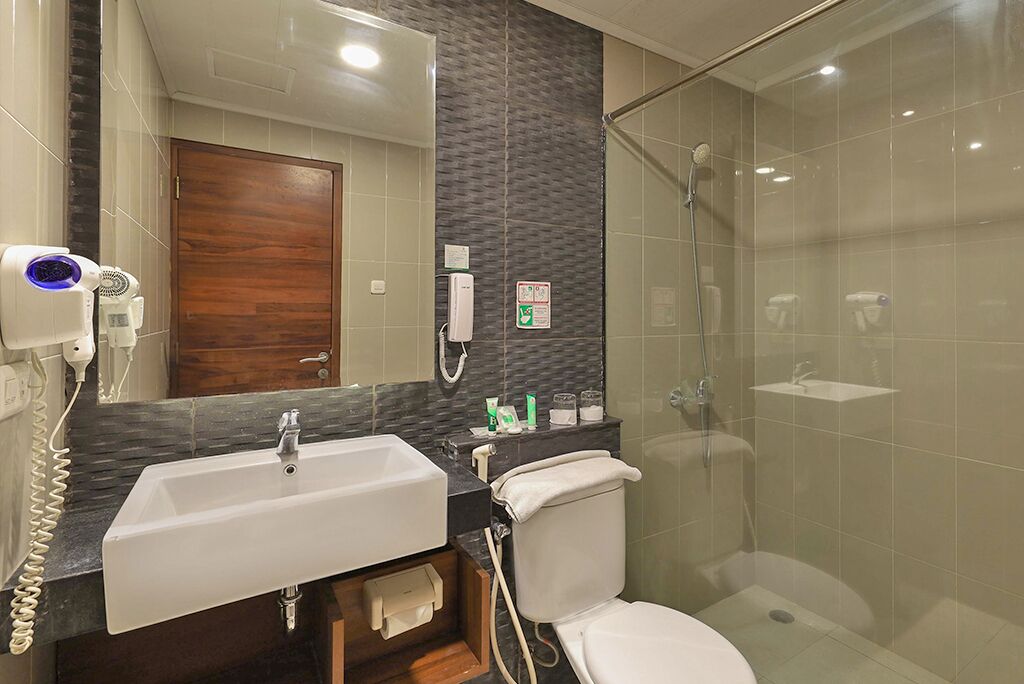 Un baño con lavamanos blanco, espejo, cabina de ducha e inodoro.