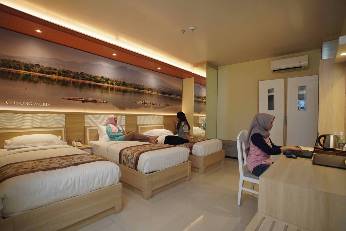 A hotel room with three beds, a desk, and a wall mural.