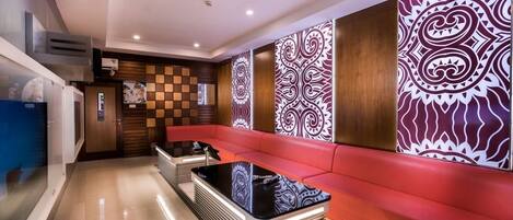 A modern lobby with a red sofa, a black coffee table, and patterned wall panels.