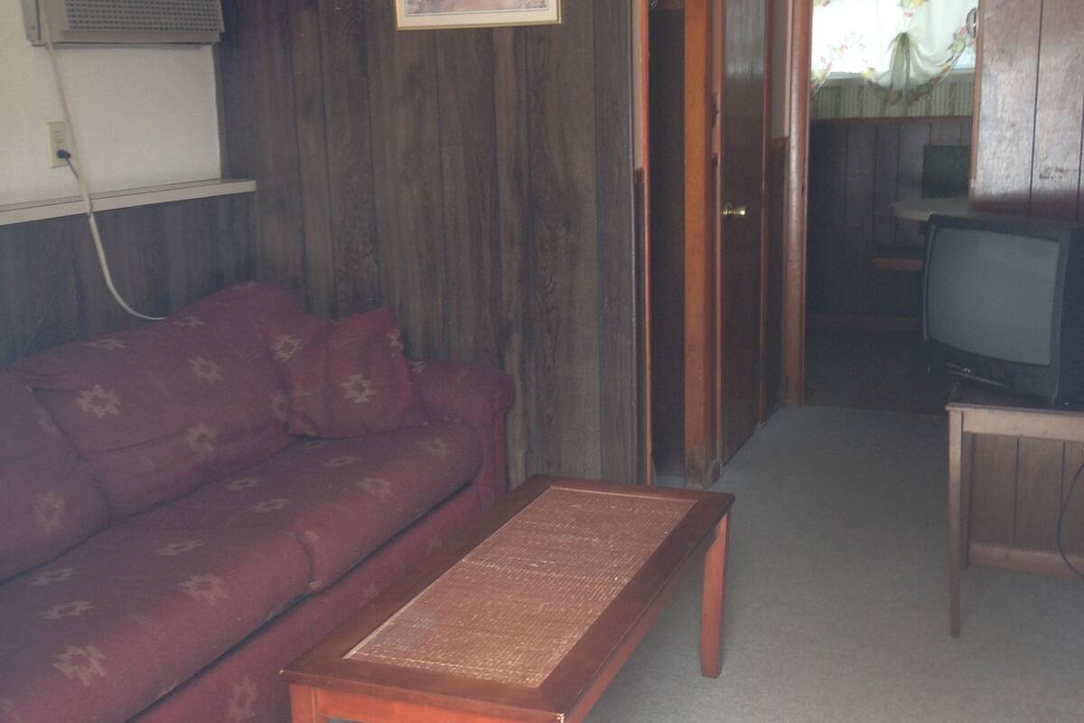 A living room with a wooden sofa, a small wooden table, and a television.