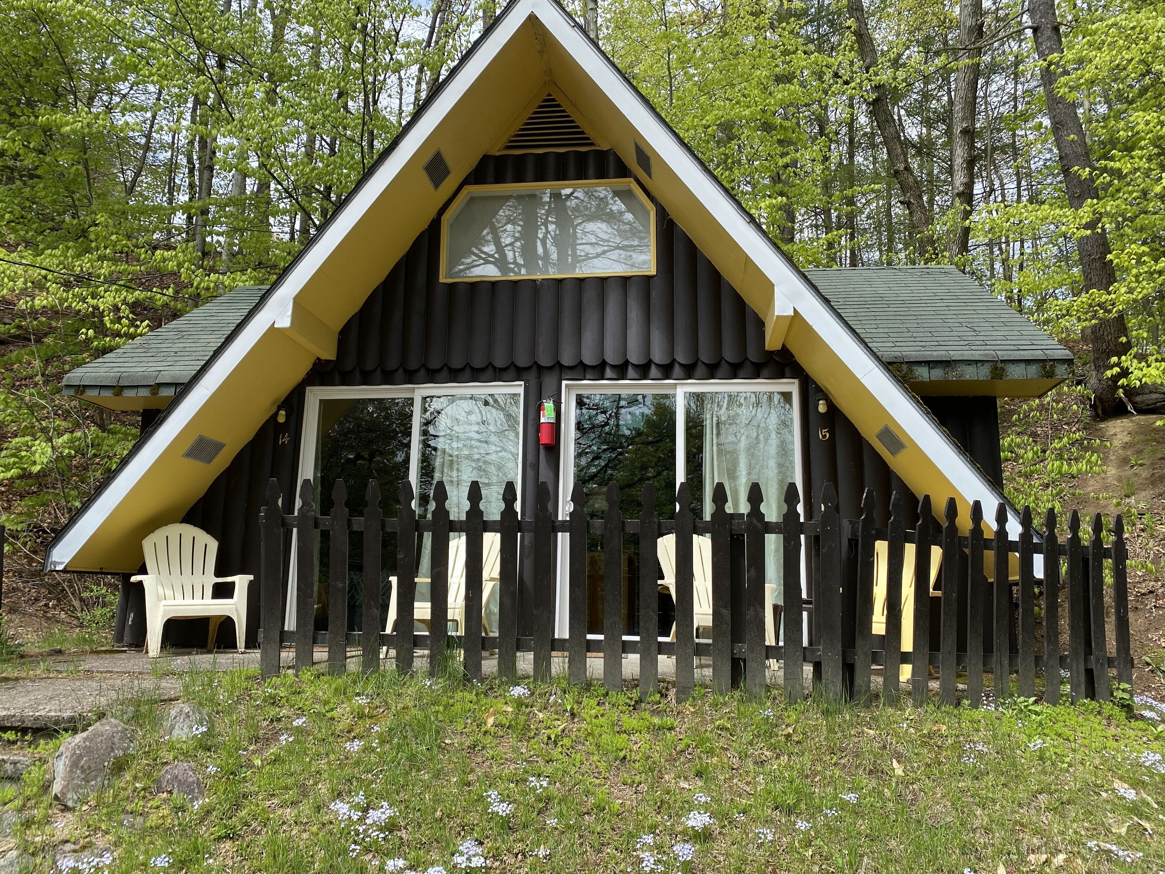 A cabin with a triangular roof, large windows, and a wooden fence.
