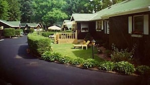 A row of cabins with a paved driveway and a grassy area with a bench and a lamp post. - Amber Lantern Lake George Motel and Cottage Rentals (Lake George)