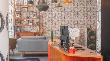 Ein modernes Wohnzimmer mit grauem Sofa, einem Holzbücherregal und einem Schreibtisch mit einem Computer.