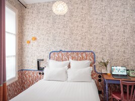 A bedroom with a bed, a desk with a laptop, and a vintage telephone.