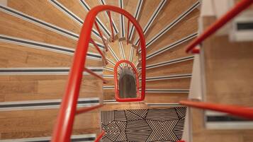 Eine Wendeltreppe mit roter Handlauf und einem geometrisch gemusterten Boden.