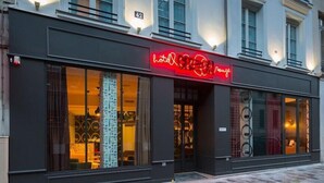 A hotel with a modern facade, large glass windows, and a neon sign. - Hôtel Crayon Rouge (Paris)