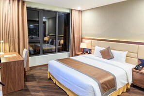 A hotel room with a large bed, a desk, and a window with curtains. - Muong Thanh Lang Son Hotel (Dong Kinh)