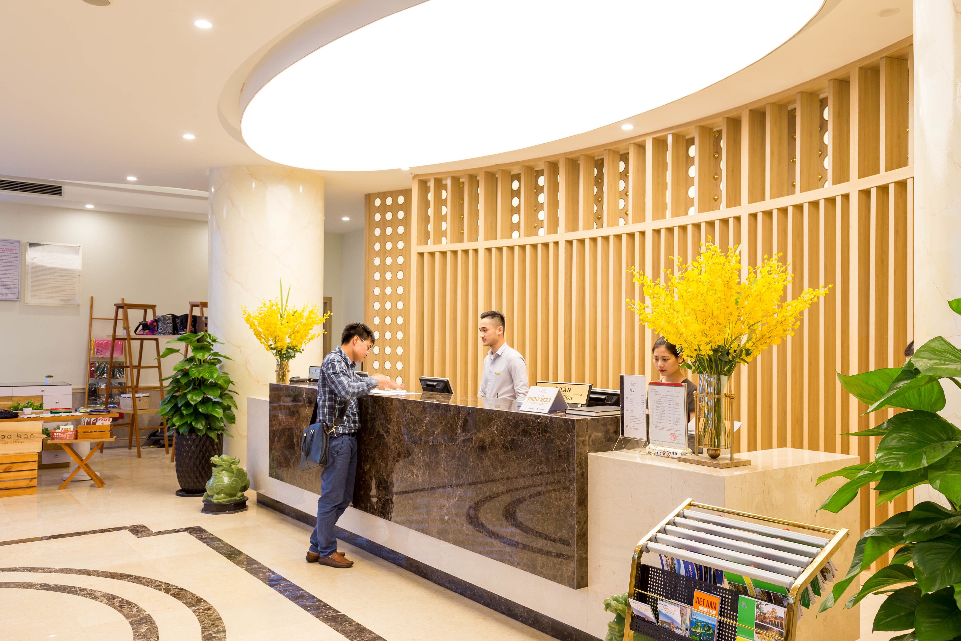 A reception area with a marble counter, wooden paneling, and potted plants.