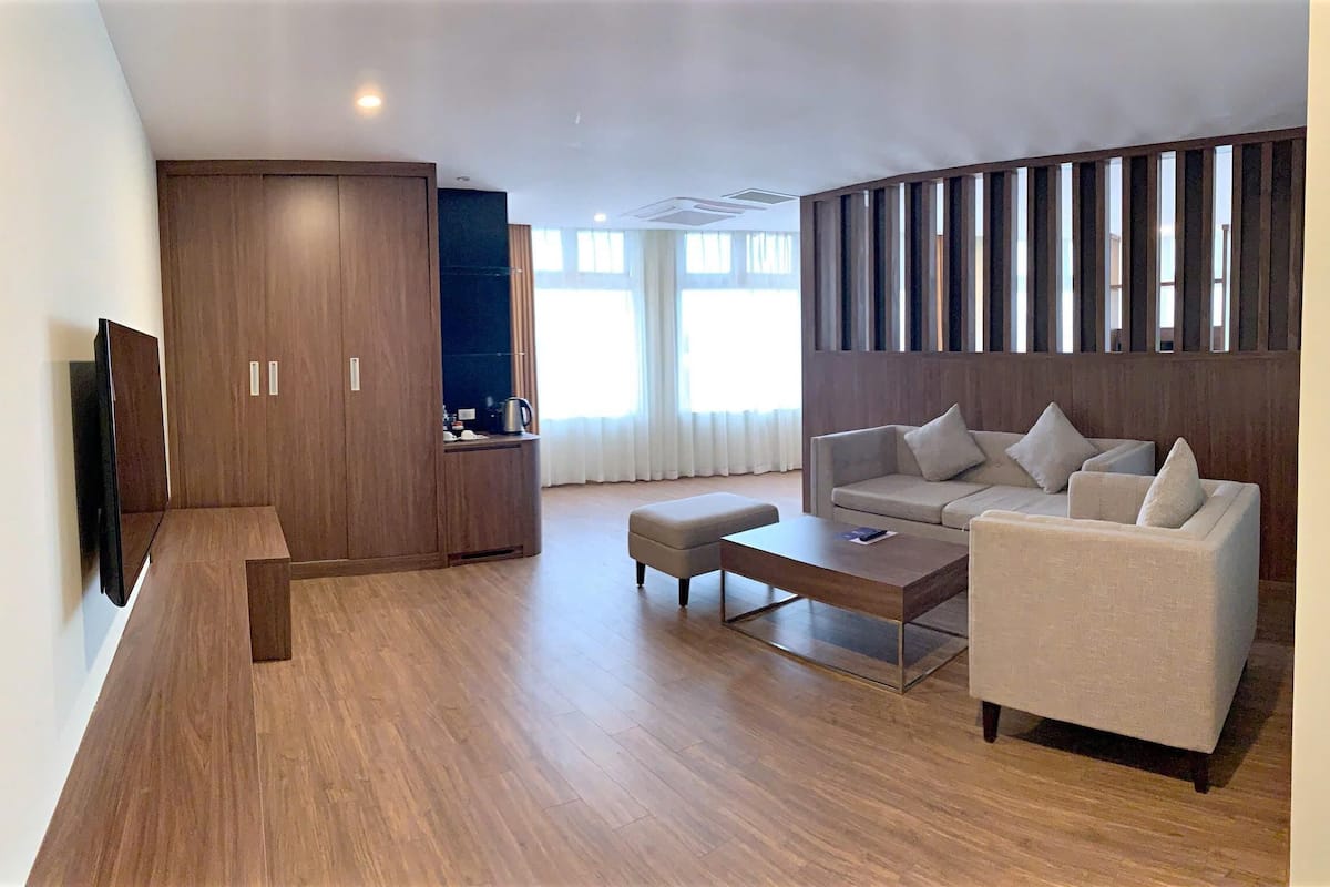 A modern living room with a sofa, ottoman, coffee table, and a TV.