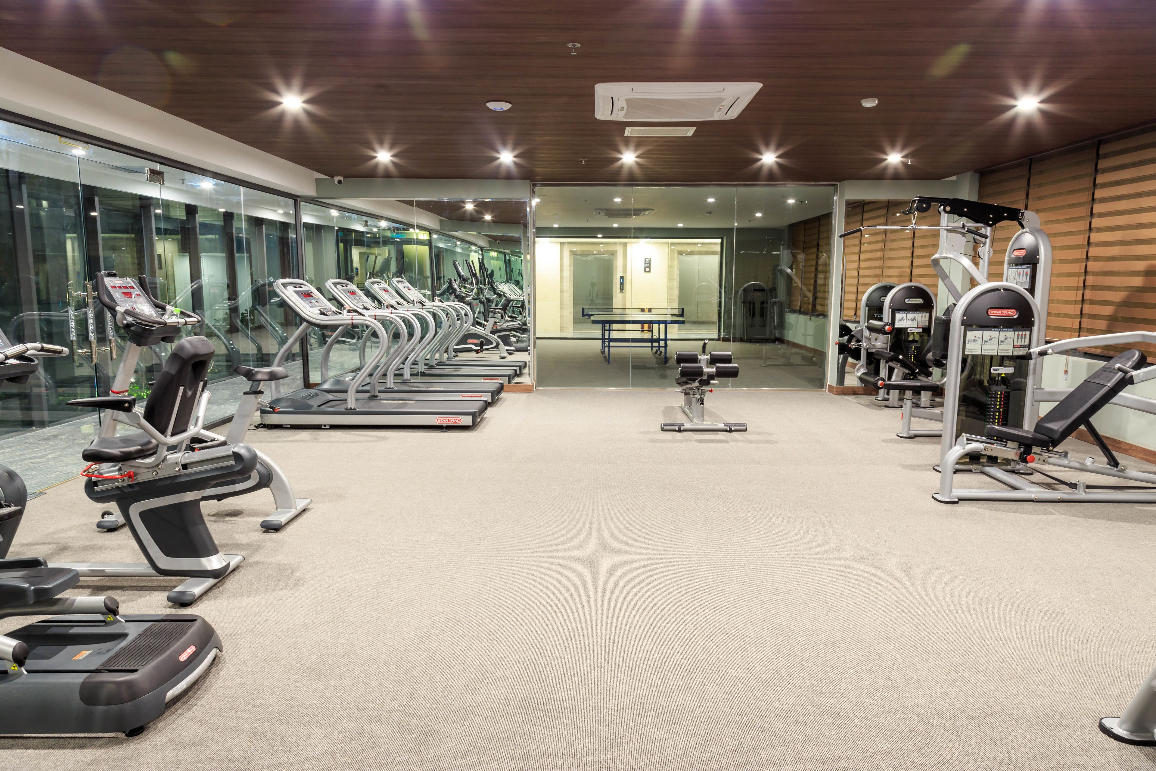 A gym with treadmills, weight machines, and a mirrored wall.