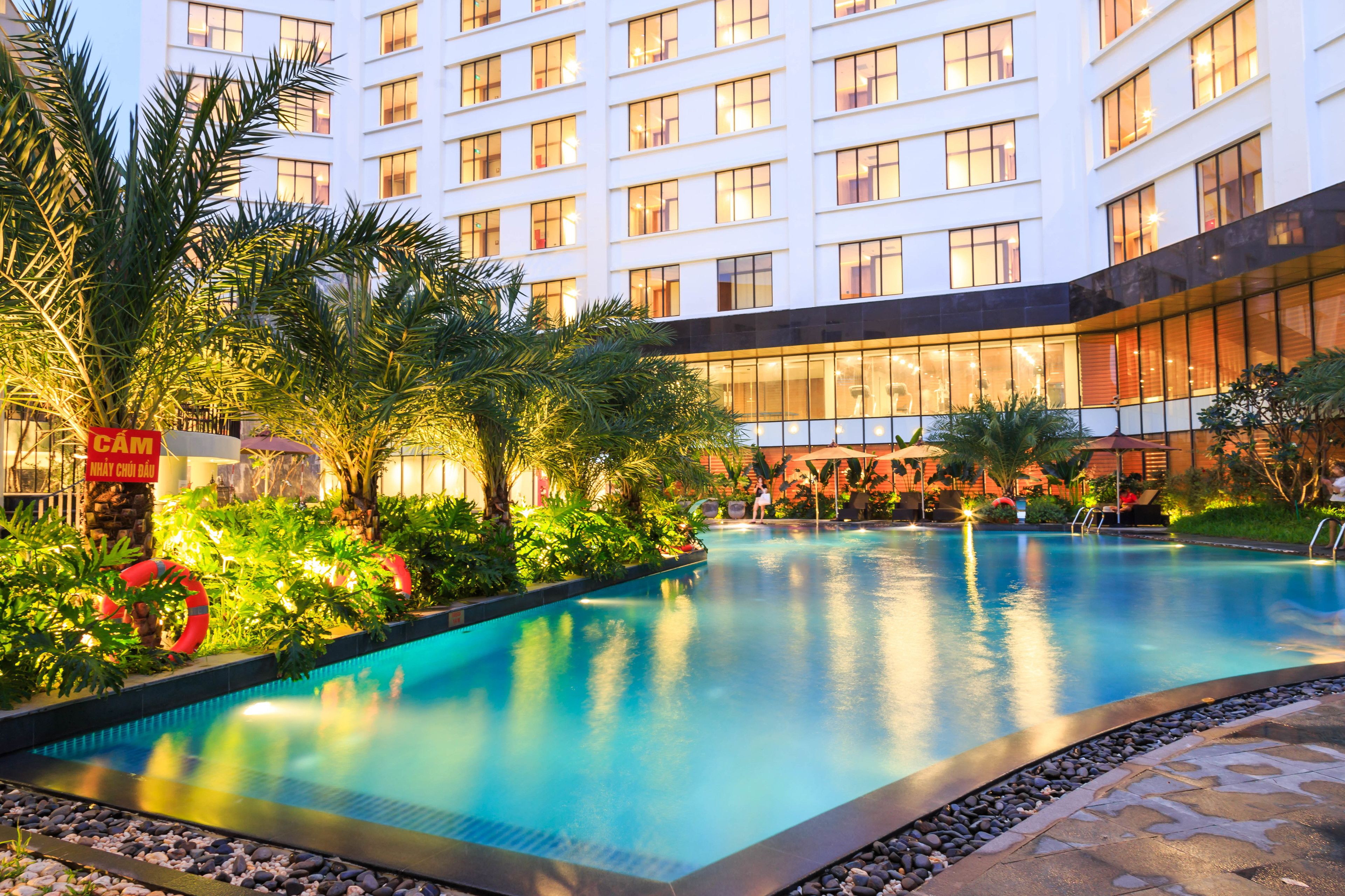 A hotel with a large indoor swimming pool surrounded by lush greenery and palm trees.