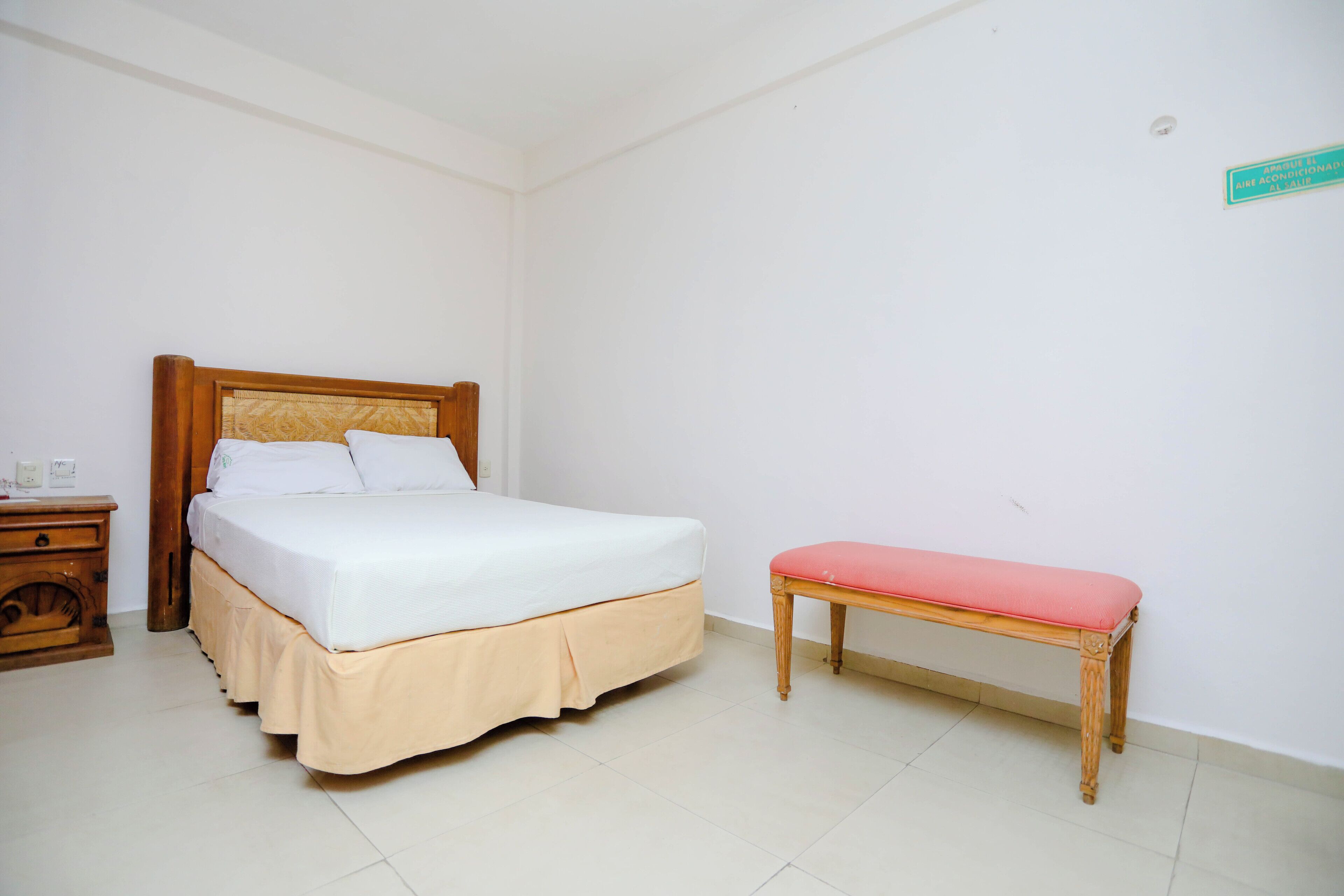 Un dormitorio ordenado con una cama, una mesita de noche y un banco.