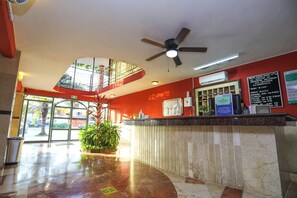A hotel reception area with a curved reception desk, a ceiling fan, a large window, and a potted plant. - Hotel Santa Maria Cancun (Cancun)