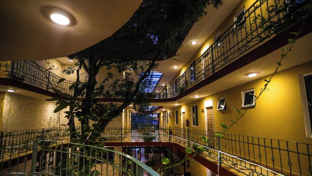 Un atrio de varios niveles con una escalera central, balcones y plantas de interior.
