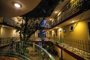 Un atrium à plusieurs niveaux, doté d’un escalier central, de balcons et de plantes d’intérieur.