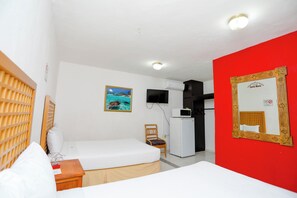 A hotel room with a bed, a chair, a TV, a refrigerator, and a red wall. - Hotel Santa Maria Cancun (Cancun)