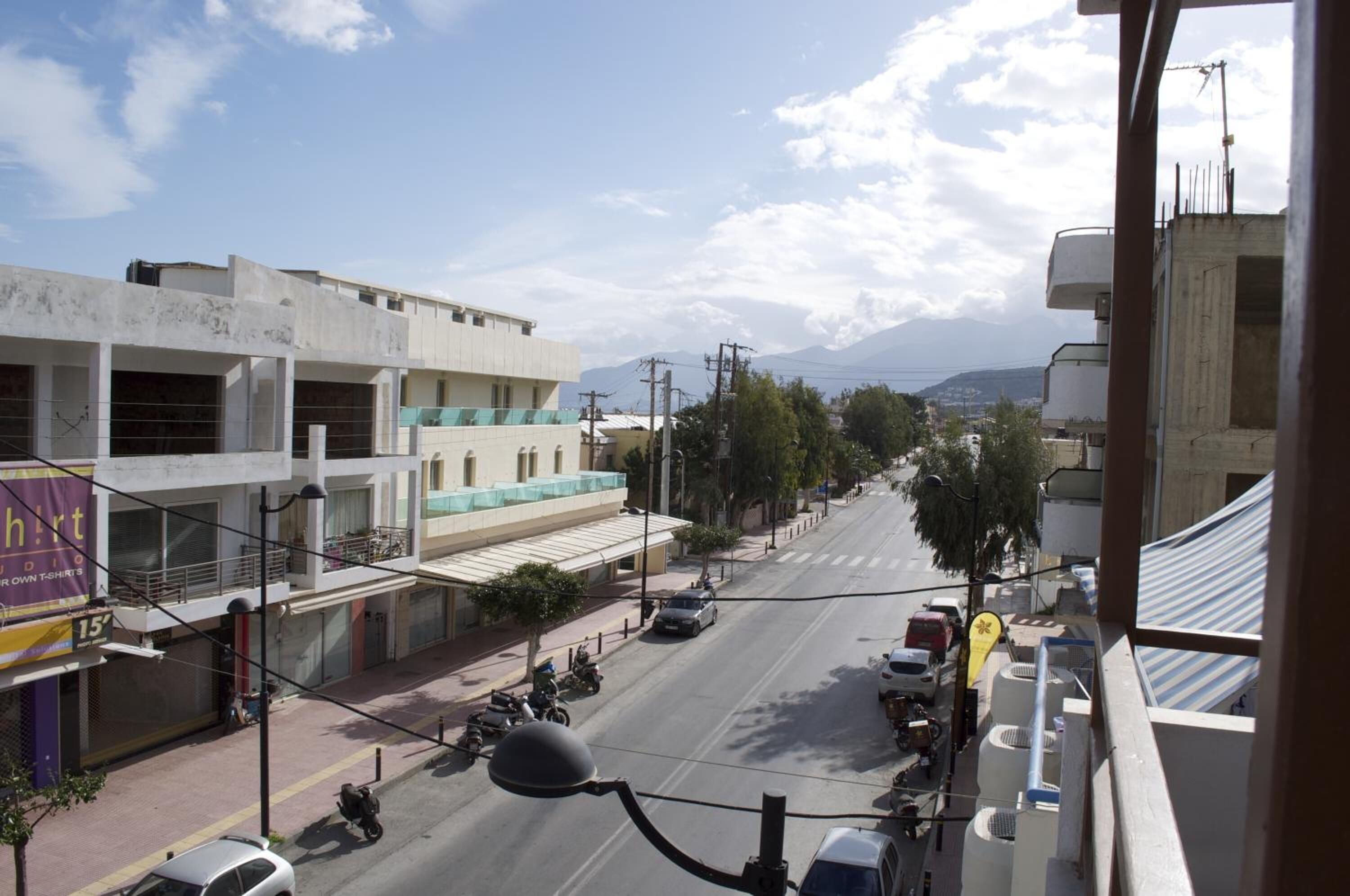 A street view with buildings, a clear sky, and distant mountains.