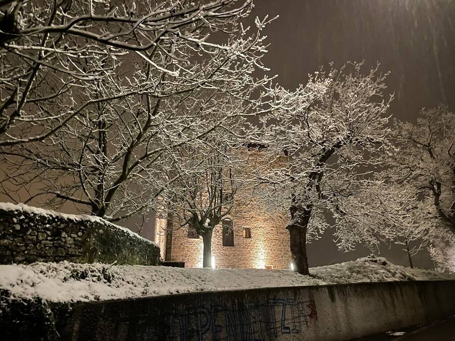 Paisaje nevado con un edificio de piedra al fondo.
