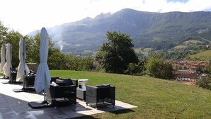 Een terras met tafels en stoelen met uitzicht op een bergachtig landschap.