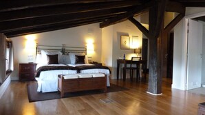 Een slaapkamer met een houten bed, nachtkastjes, een bureau en een stoel.