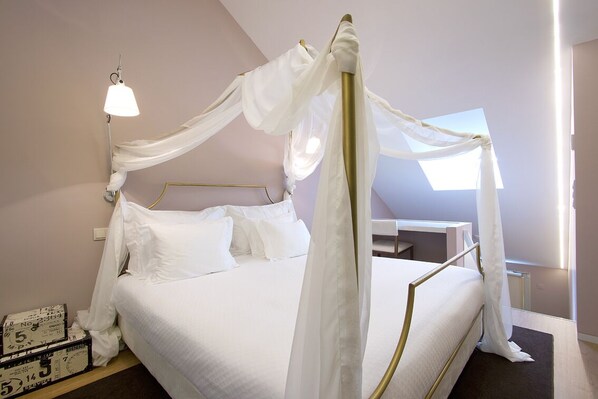 A bed with a canopy, a bedside lamp, and a suitcase on the floor.