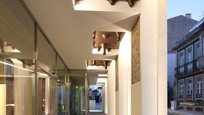 A corridor with glass walls, a tiled floor, and a ceiling with a unique design.