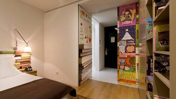 Une chambre à coucher avec un lit, une lampe de chevet et une bibliothèque remplie de livres.