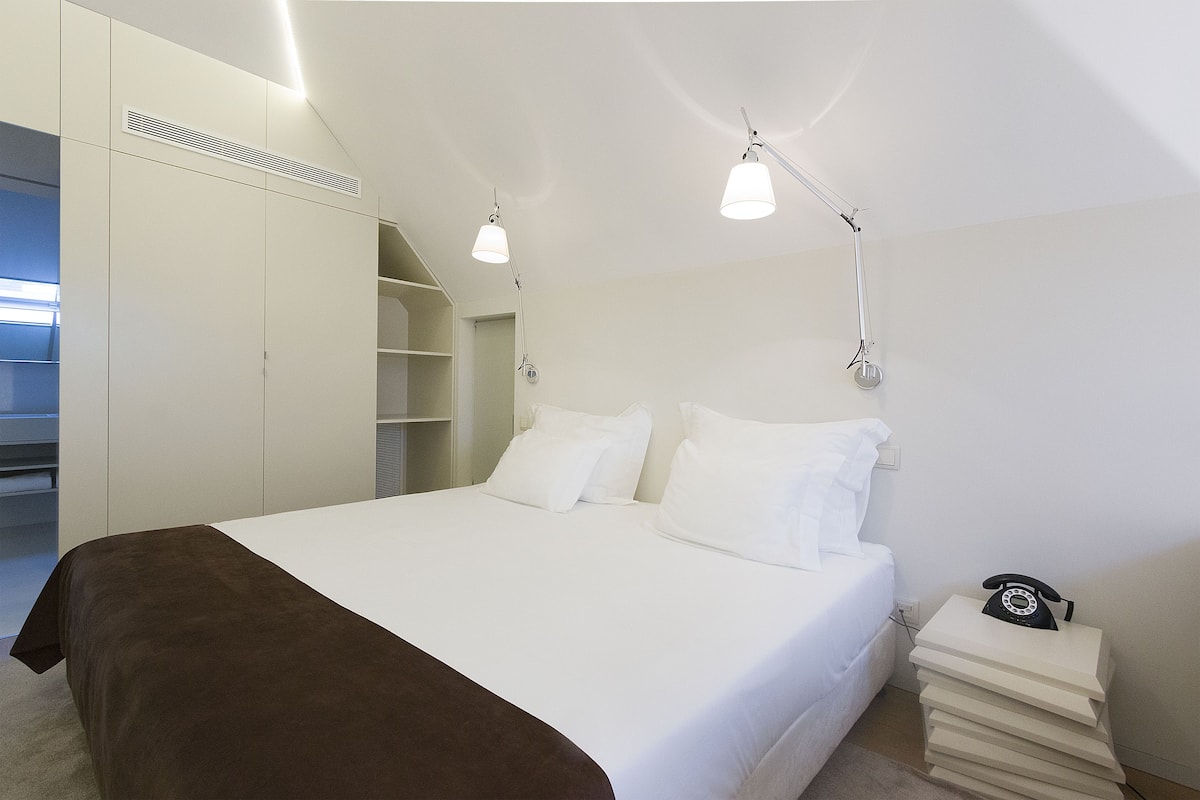 A bedroom with a bed, bedside tables, a telephone, and a wardrobe.