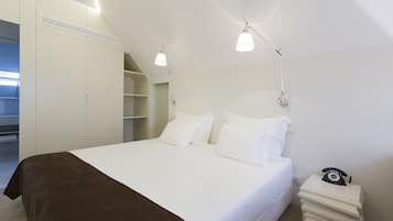 Ein Schlafzimmer mit einem Bett, Nachttischen, einem Kleiderschrank und einem Schreibtisch mit Telefon.