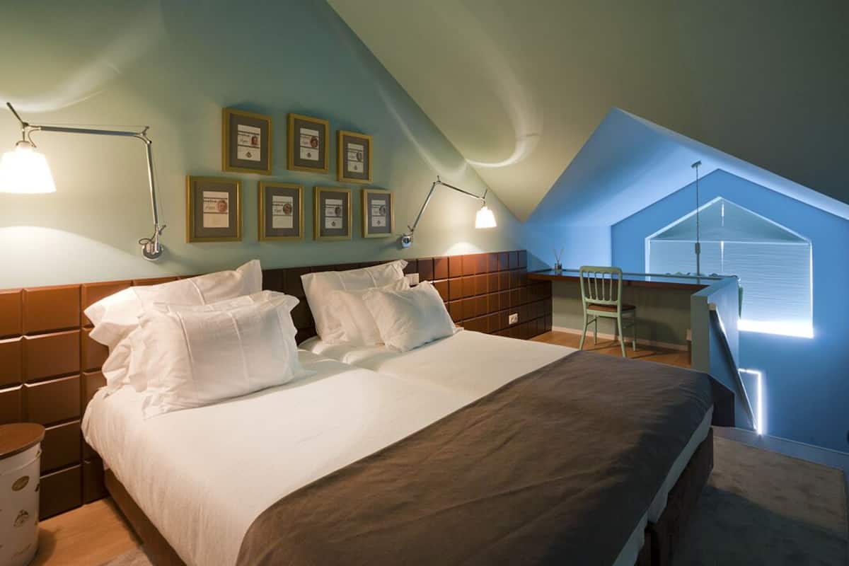 Ein Schlafzimmer mit einem großen Bett, zwei Nachttischen, einem Schreibtisch und einem Stuhl. An der Wand befinden sich gerahmte Zertifikate.