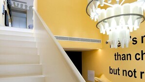 A staircase with a yellow wall and a unique chandelier.