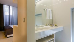 A modern bathroom with a large mirror, white sink, and a towel rack.