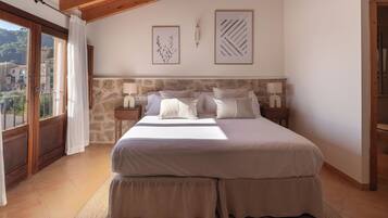 A bedroom with a large bed, stone headboard, two bedside tables with lamps, and framed artwork on the wall.