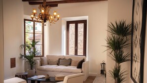 Ein Wohnzimmer mit Sofa, Sessel, Couchtisch und Zimmerpflanzen.