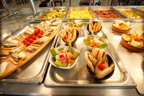 Un bufé con diversas opciones de comida, incluyendo mariscos, ensaladas y frutas.