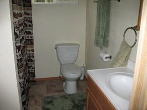 A small bathroom with a toilet, sink, and shower curtain.