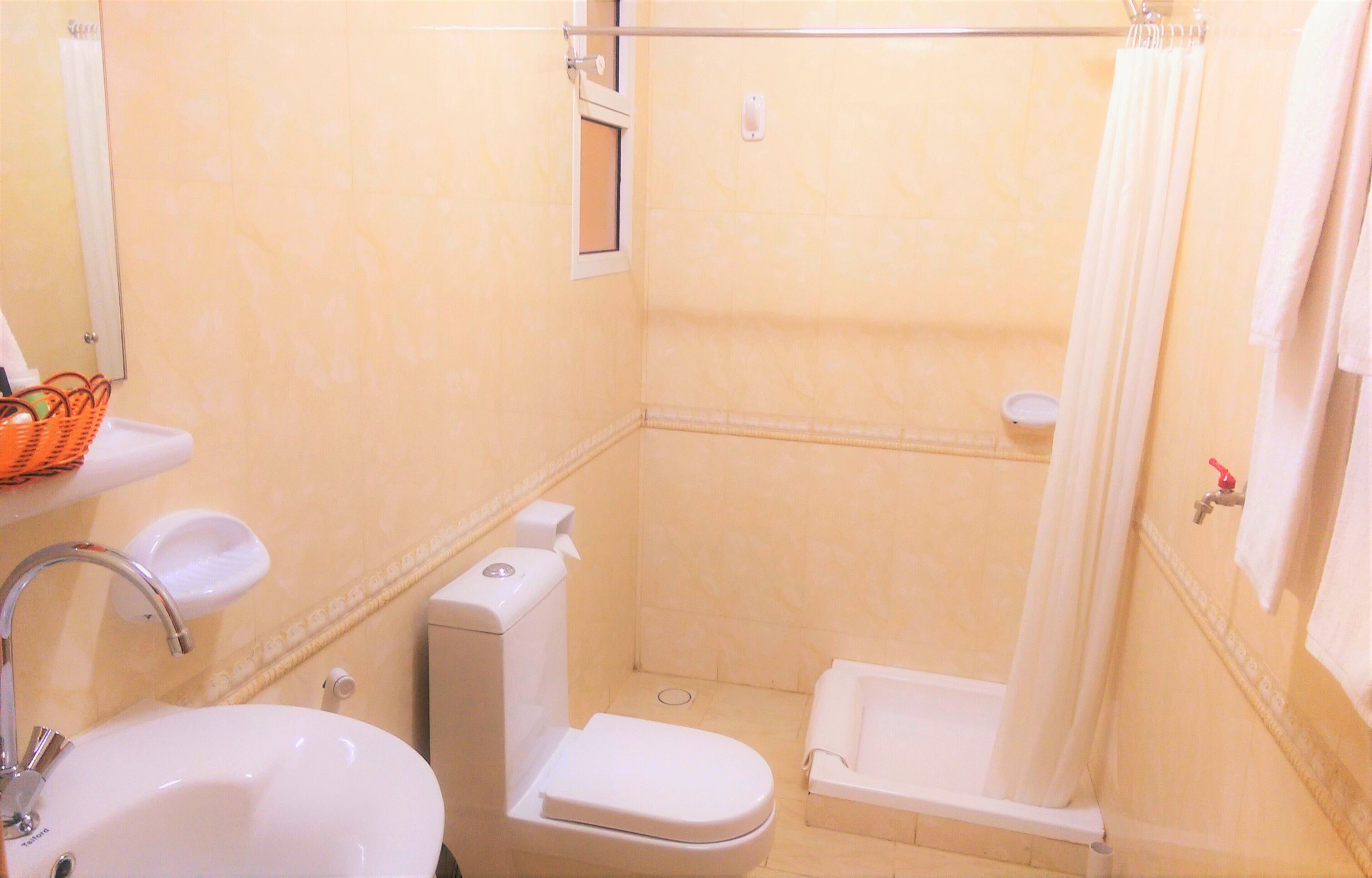 A small bathroom with a toilet, sink, and shower.