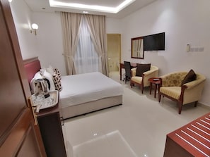 Ein Hotelzimmer mit Bett, Schreibtisch, Stuhl, Fernseher und Nachttisch.