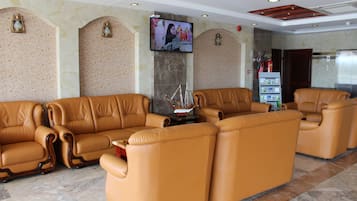 Un hall con sofás de cuero, una televisión, chimenea y máquina expendedora.