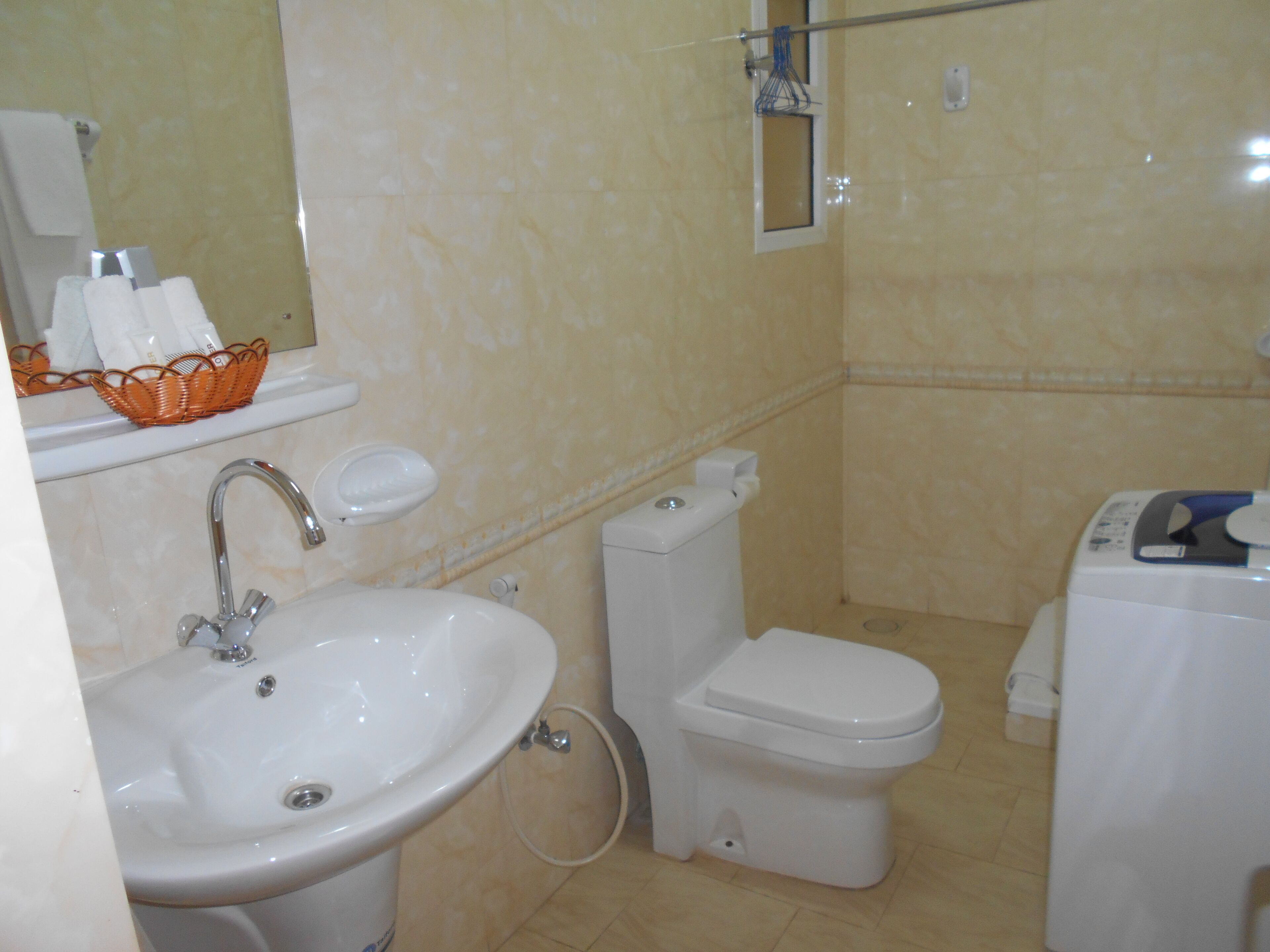 A bathroom with a sink, toilet, and a small window.