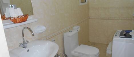 A bathroom with a sink, toilet, and a small window.