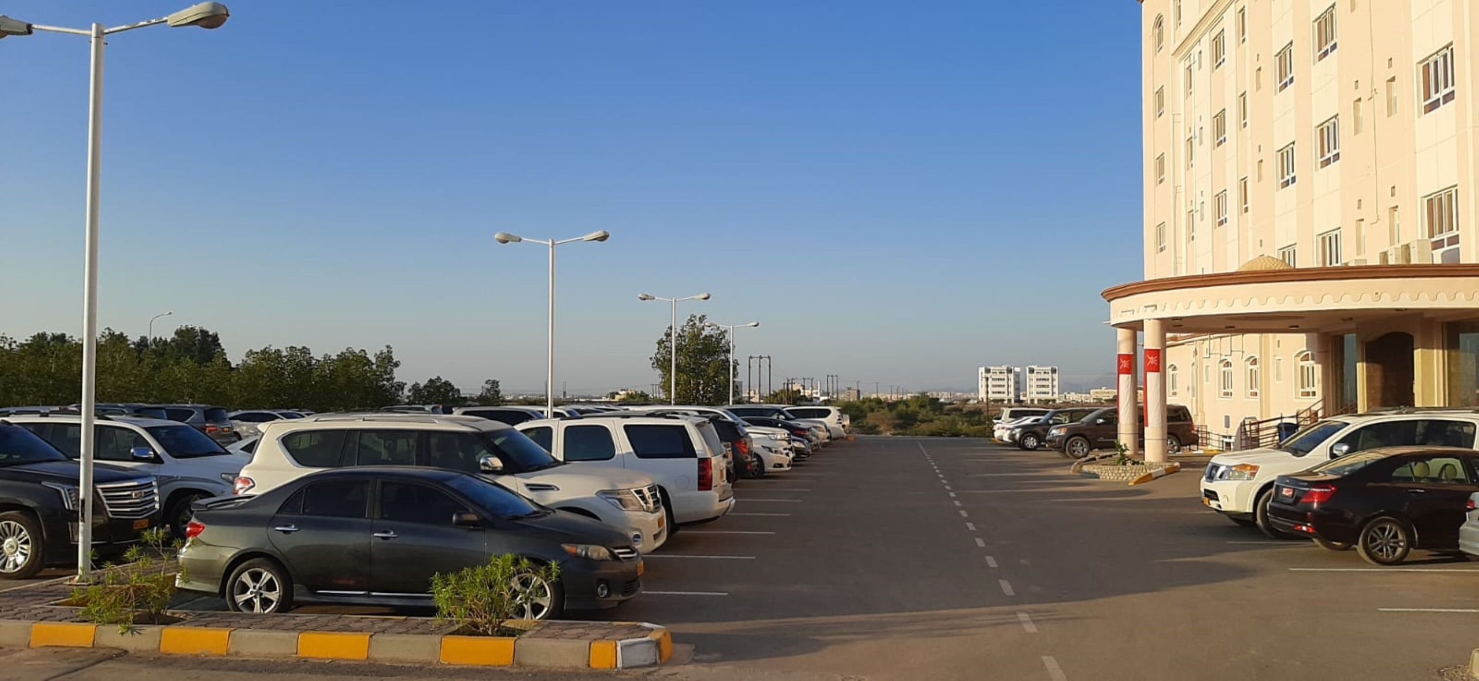 A parking lot with multiple cars and a building with a circular entrance.