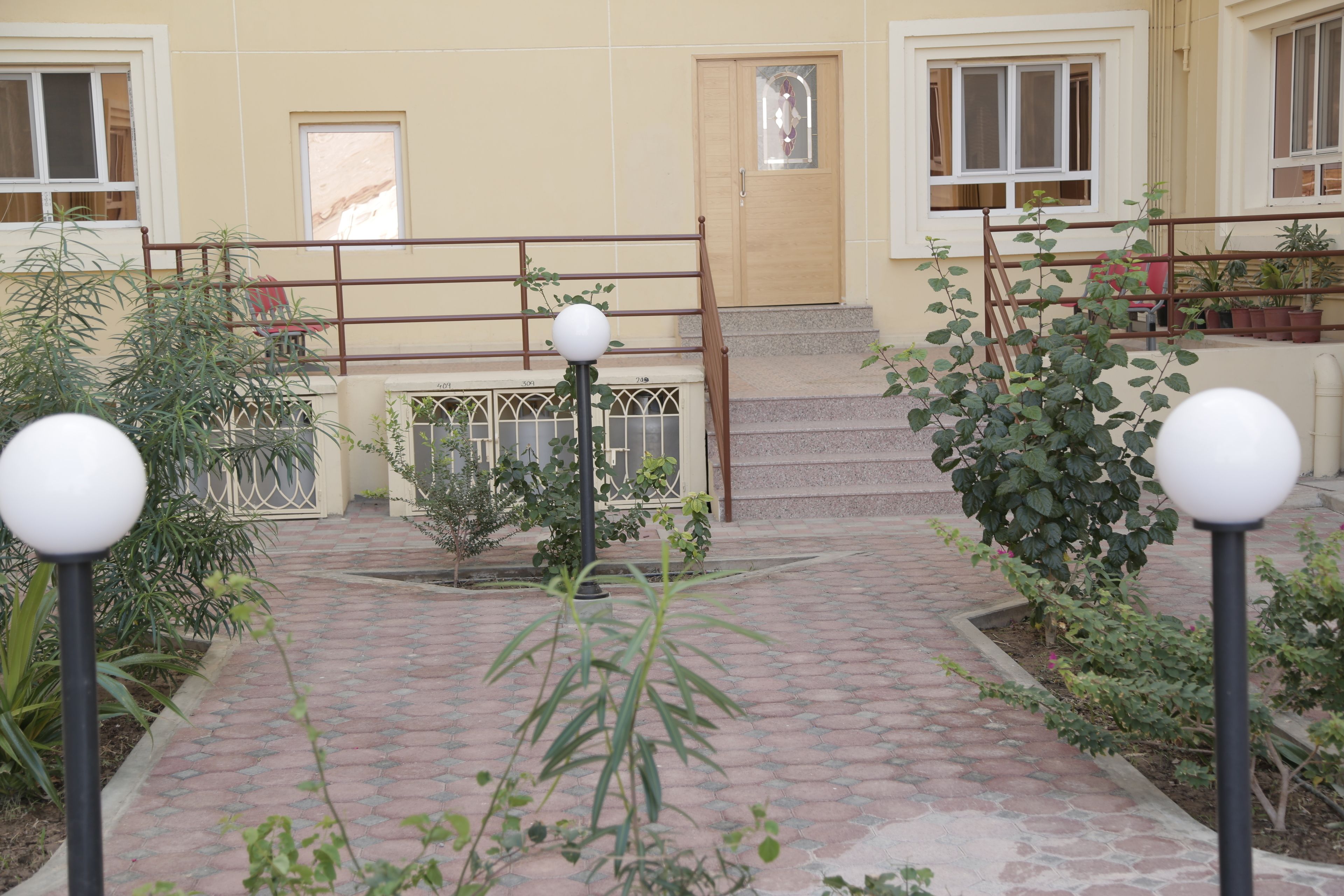 Un patio con un sendero de baldosas, una escalera de madera y plantas en macetas.