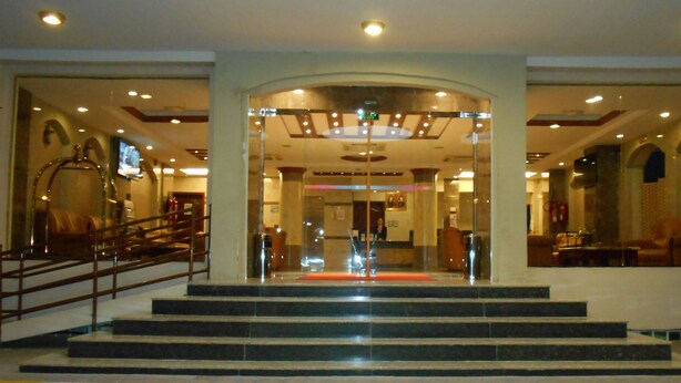 Un vestíbul d'hotel amb una imponent escala, una recepció i zones d'estar.