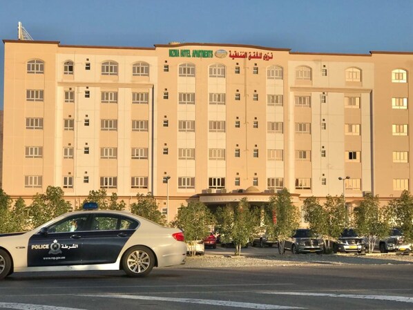A multi-story building with a sign that reads "Naznia Hotel Apartments" in English and Arabic. - Nizwa Hotel Apartments (Nizwa)