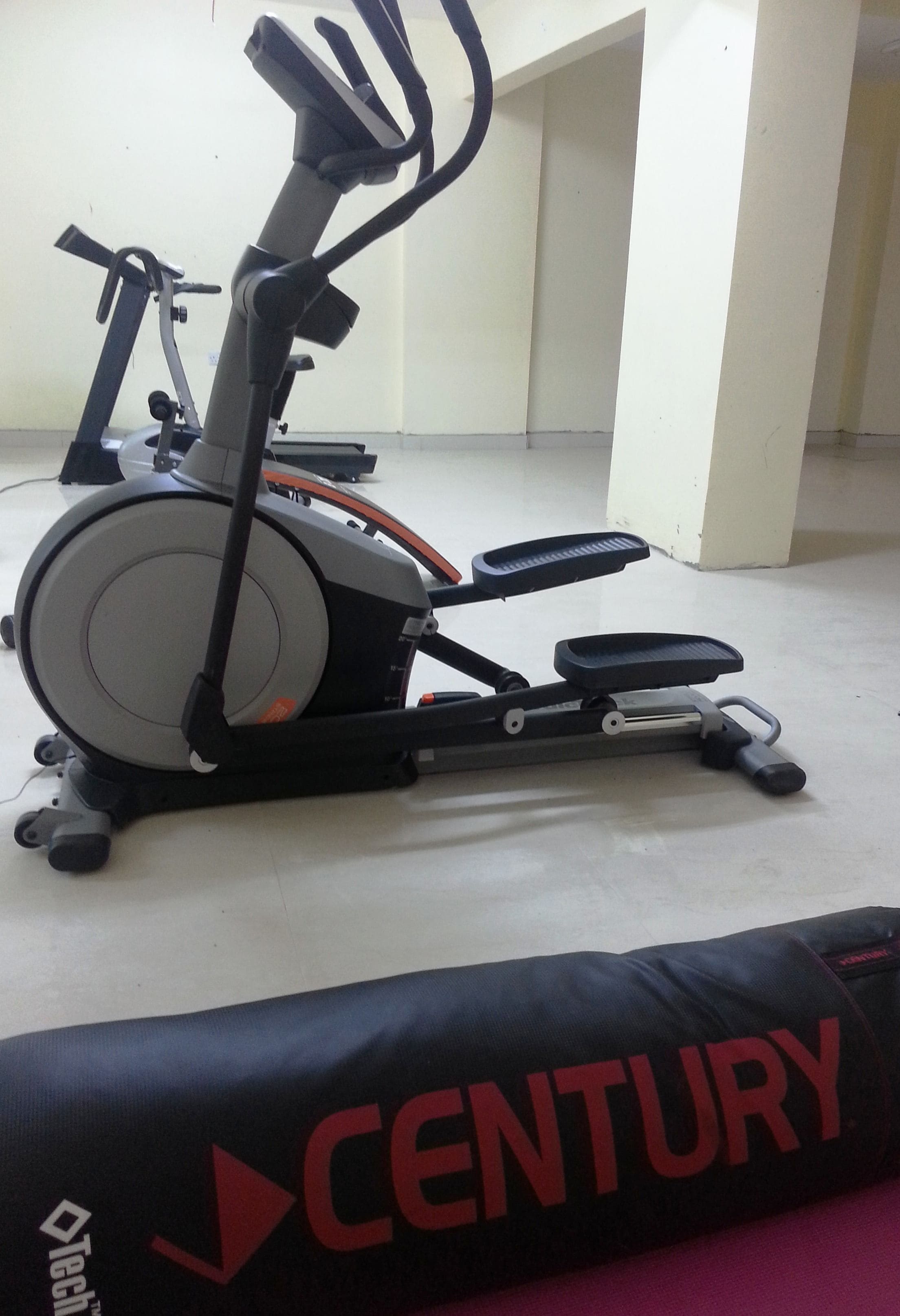 An exercise machine and a black mat with "CENTURY" written on it.