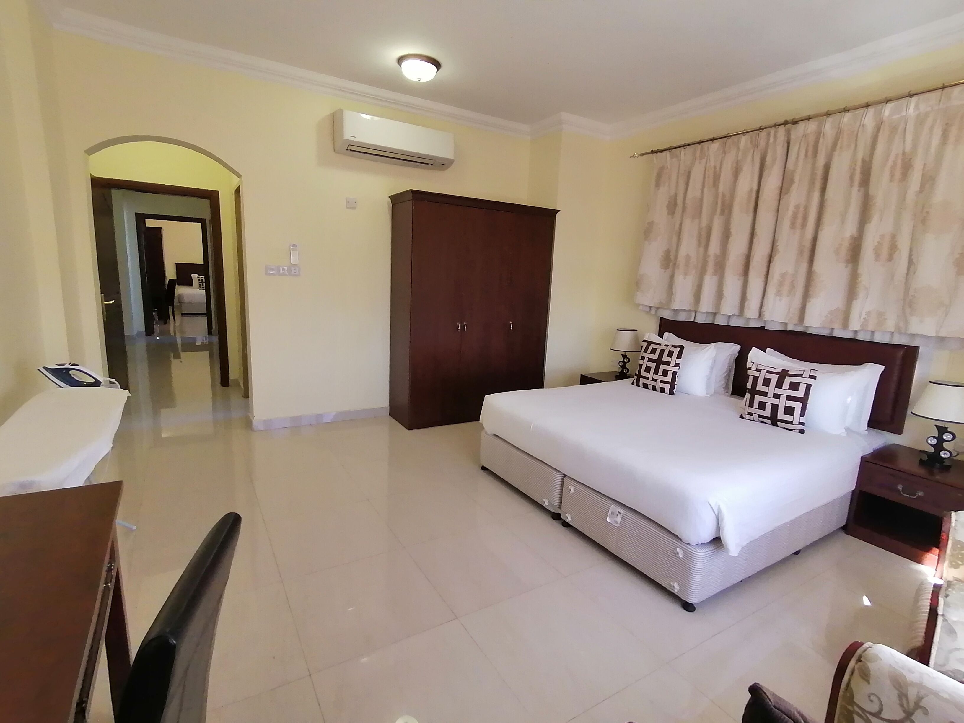 Hotelkamer met een bed, nachtkastjes, een kledingkast, een airconditioning en een zichtbare badkamer door een boog.